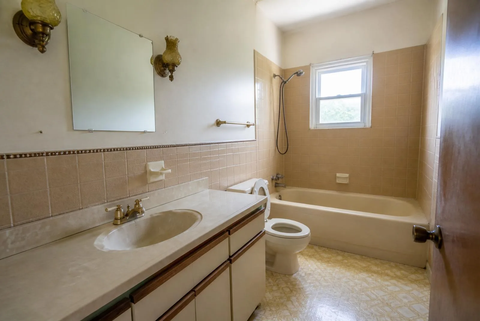 Dated bathroom with beige tile and an old laminate vanity